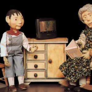 Abuela leyendo un cuento a su nieto. Marionetas del espectáculo La Bella Durmiente